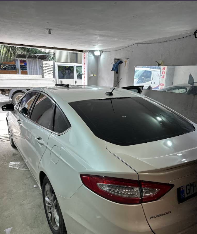 White Ford Fusion with freshly tinted rear glass in the workshop
