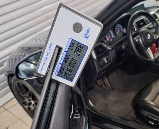 VLT meter measuring light transmission on a tinted BMW window