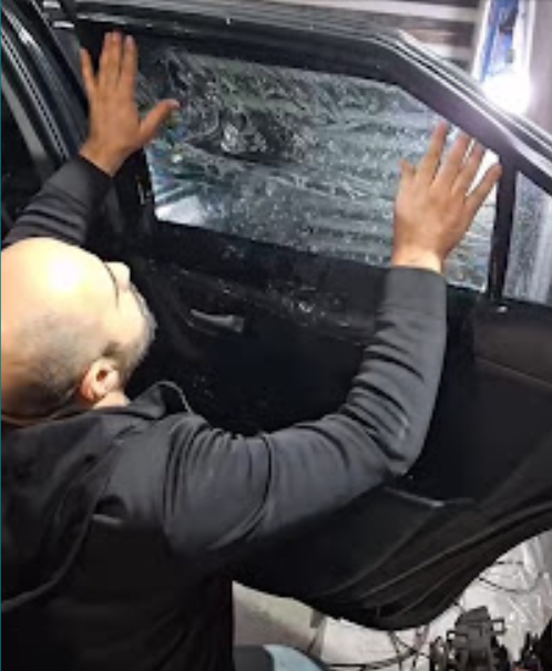 Technician fitting tint film on a car door window